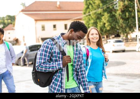 Gruppo di amici multietnici che camminano in città Foto Stock