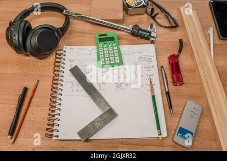 Posa piana di attrezzi per la pianificazione della lavorazione del legno, compresi il pattino di schizzo, gli strumenti di misura e la calcolatrice. Foto Stock