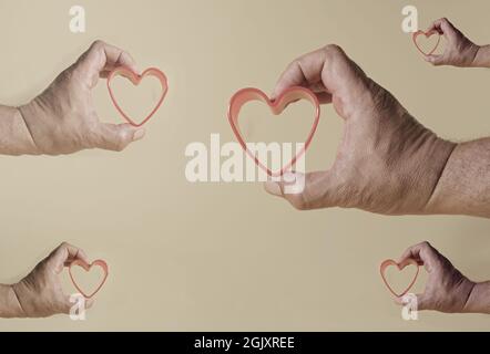 Un concetto di amore su uno sfondo isolato. La mano di un uomo tiene un cuore rosso. Foto Stock