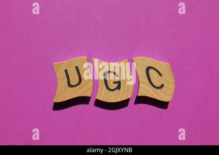 UGC, acronimo di User Generated Content in wooden alfabet letters isolato su sfondo viola Foto Stock