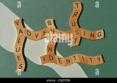 Pubblicità, marchio, identità, valori, fiducia, parole in lettere in alfabeto di legno in forma di parola incrociata isolato su sfondo verde Foto Stock