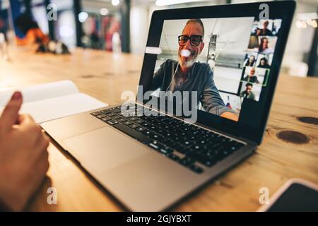 Donna d'affari anonima che partecipa a una riunione virtuale in un ufficio moderno. Donna d'affari irriconoscibile che usa un laptop per una videoconferenza con il suo pa Foto Stock