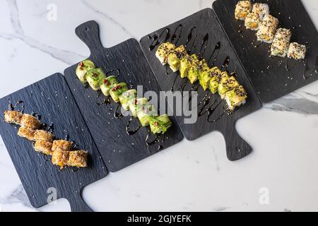 Una vista dall'alto dei set di sushi roll su tavole nere Foto Stock
