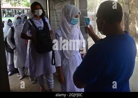 Dhaka, Bangladesh. Settembre 12, 2021. Un funzionario controlla la temperatura corporea di uno studente al suo arrivo alla scuola e al college delle ragazze del governo di Azimpur a Dhaka, Bangladesh, il 12 settembre 2021. Dopo 543 giorni, le scuole primarie, secondarie e superiori in tutto il paese riaprirono mantenendo le linee guida e i protocolli sanitari del Covid-19. Credit: Mamunur Rashid/Alamy Live News Foto Stock