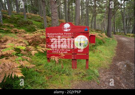 Insegna rossa e bianca per Rochiemurchus Forest Wildlife Conservation Area nel Cairngorms National Park. Percorso e sfondo offuscato foresta. Foto Stock