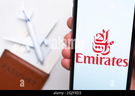 Logo della compagnia aerea Emirates sullo schermo del telefono cellulare in mano uomo sullo sfondo del passaporto, carta d'imbarco e aereo, settembre 2021, San Foto Stock