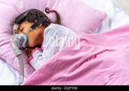 Bambino affetto da apnea del sonno, utilizzando una macchina CPAP Foto Stock