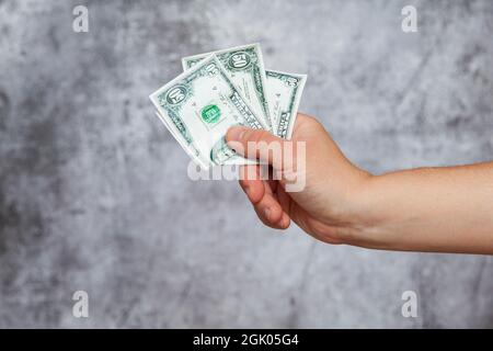 Una mano destra dell'uomo che tiene tre fatture cinquanta del dollaro su uno sfondo grigio testurizzato. Foto Stock