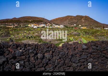 Vista caratteristica del muro di pietra arenaria costruito con pietre laviche, sullo sfondo la città di Linosa Foto Stock