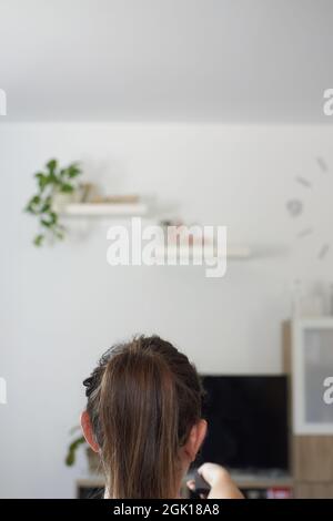 Una donna che accende la televisione si rilassò sul divano Foto Stock