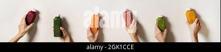 Mani umane che tengono succhi freschi in bottiglie, composizione ampia Foto Stock