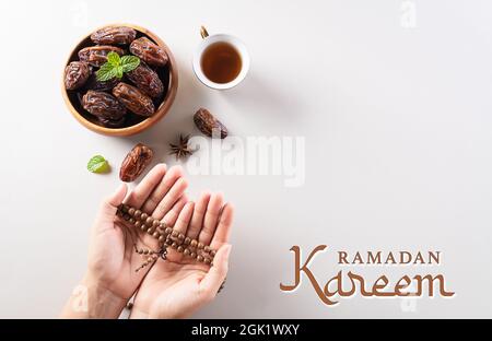 Tabella vista dall'alto immagine della decorazione Ramadan Kareem sfondo, datteri frutta, caffè e mano con perline di rosario. Foto Stock