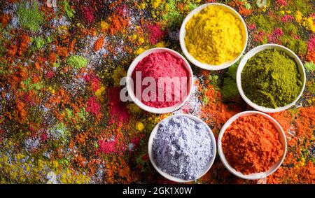 Festa Holi. Tradizionale indiano Holi colori decorazione a polvere con vernici. Vista dall'alto dei colori Gulal organici sullo sfondo delle ciotole. Foto Stock