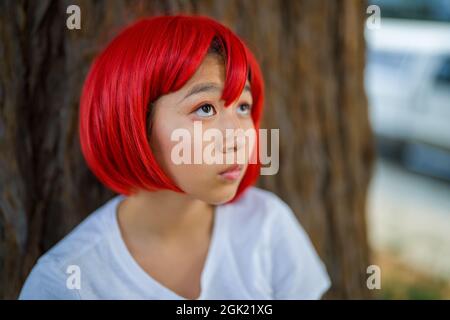 Red Blood Cell Cosplay attrice in piedi con Redwood Tree | ragazza asiatica teen con Red Wig Foto Stock