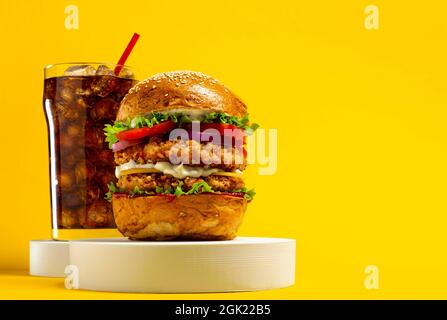 Delizioso hamburger con cola su sfondo giallo Foto Stock