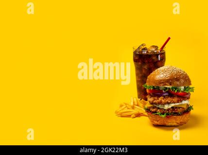 Delizioso hamburger con cola e patatine fritte su sfondo giallo Foto Stock