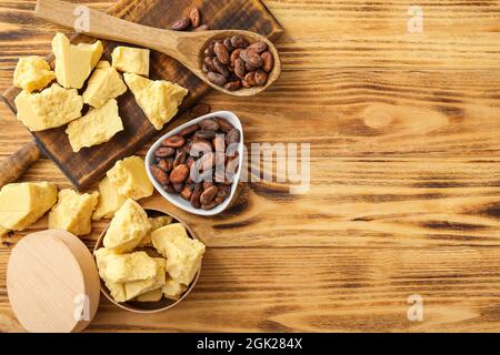 Versare con il cacao in grani e il burro su sfondo di legno Foto Stock