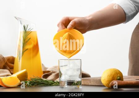 Donna che versa succo d'arancia in vetro sul tavolo in cucina Foto Stock