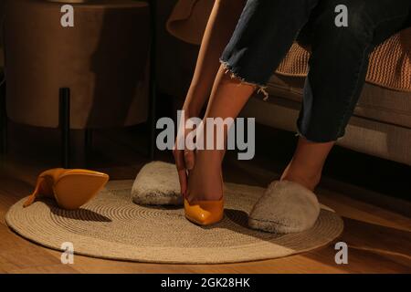 Donna che mette su ciabatte calde a casa dopo la giornata di lavoro, primo piano Foto Stock