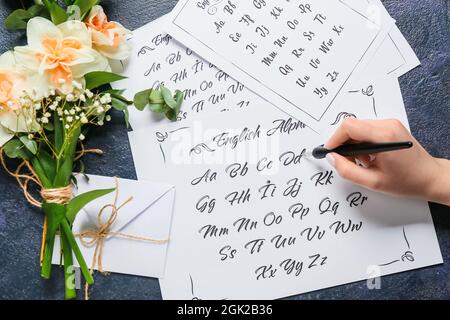 Donna che scrive alfabeto inglese su sfondo scuro Foto Stock