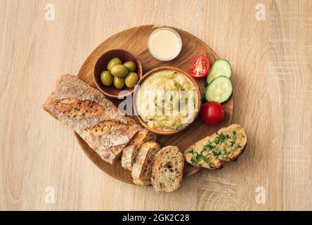 Ciotola con gustosa ghanoush di babà, pane e verdure su sfondo di legno Foto Stock