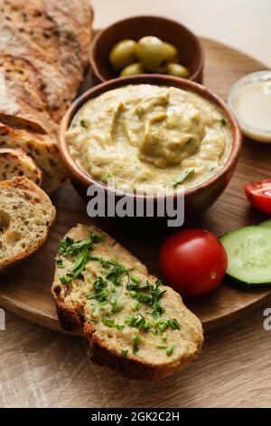 Ciotola con gustosa ghanoush babà, pane e verdure su sfondo di legno, primo piano Foto Stock