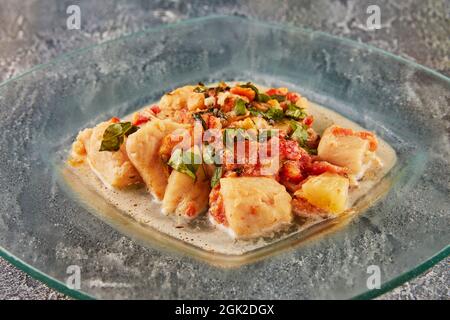 Branzino con pomodori finocchi e basilico in salsa su un piatto di vetro. Foto Stock