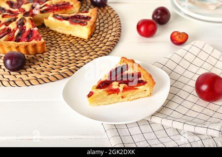 Piatto con pezzo gustoso torta di susina su sfondo di legno chiaro Foto Stock