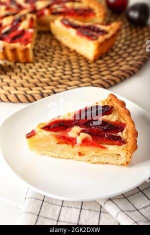 Piatto con pezzo di gustosa torta di susina su sfondo chiaro, primo piano Foto Stock