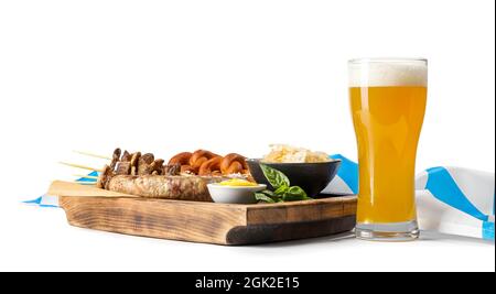 Tavola di legno con gustose salsicce bavaresi, spuntini e birra su sfondo bianco. Festa dell'Oktoberfest Foto Stock