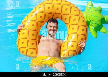 Giovane uomo con anello gonfiabile in piscina Foto Stock