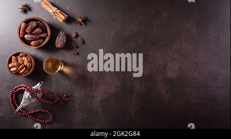 Tabella vista dall'alto immagine della decorazione Ramadan Kareem, datteri frutta, lampada aladdin, tè e perline rosarie su sfondo di pietra scuro. Disposizione piatta con spazio di copia. Foto Stock