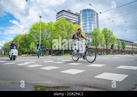 Amsterdam Paesi Bassi - Agosto 20 2017; ciclisti, ciclomotori e auto attraversano insieme l'incrocio in città Foto Stock
