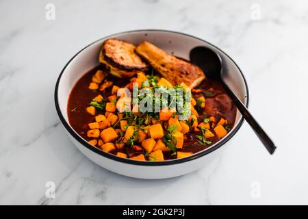 curry di pollo al burro vegano con sudore di zucca e parsnip sormontato con cioriandro fresco di produzione propria, ricette salutari a base di piante Foto Stock