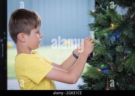 Ritratto di un ragazzo che decora l'albero di Natale a casa in Australia Meridionale Foto Stock