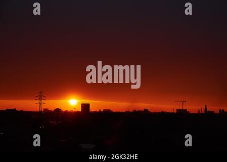 Tramonto su paesaggio urbano. Edifici sikhouettes in città e costruzione gru al tramonto Foto Stock