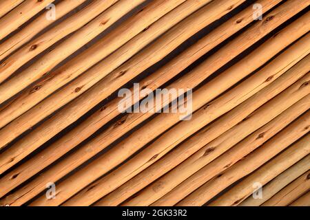 Primo piano vista astratta di pali di bambù di legno diagonalmente stattati legati insieme in una fila per formare una partizione o un muro Foto Stock