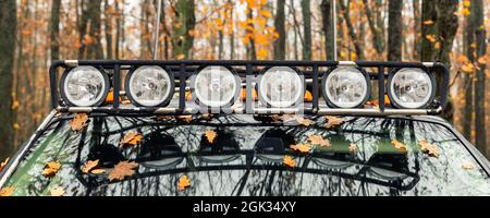 Vista dettagliata della barra del portapacchi realizzata su misura con faro supplementare montato sul tetto della macchina suv pick up per impieghi pesanti contro la nebbia della foresta autunnale Foto Stock