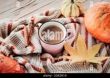 Una tazza di caffè latte sul tavolo con zucche, anice stellato e bastoncini di cannella su un maglione a maglia. Autunno concetto, vista dall'alto. Foto Stock