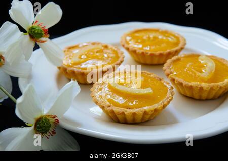 Bánh tart chanh, bánh trứng đường nhỏ, chanh lát Foto Stock