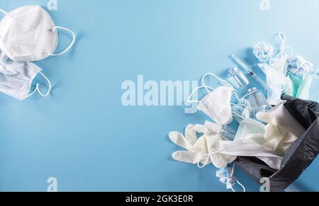 Covid-19 rifiuti di plastica e rifiuti, maschere monouso, guanti da medico, bottiglia di alcool gel e ago in cestino. Pila di dispositivi di protezione personale usati Foto Stock