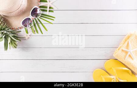 Vacanza estiva, viaggio e vacanza concetto. Occhiali da sole, stelle marine, cappello da spiaggia, conchiglia e maschera medica per proteggere il cocid-19 su sfondo bianco di legno Foto Stock