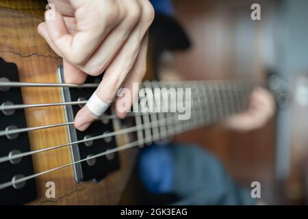 Musicista che suona il basso elettrico con il dito ferito Foto Stock