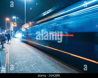 il tram lascia la fermata nella città di notte, vista di movimento sfocato Foto Stock