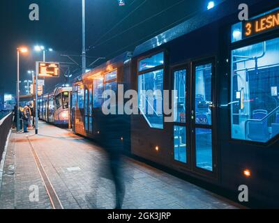 il tram lascia la fermata nella città di notte, vista di movimento sfocato Foto Stock