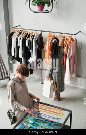 Due giovani donne che scelgono abiti e accessori nuovi nel centro commerciale Foto Stock