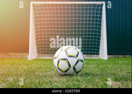 Pallone da calcio su erba verde di fronte al cancello con rete Foto Stock