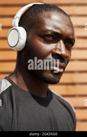 Primo piano di un uomo africano che ascolta la musica in cuffia all'aperto Foto Stock