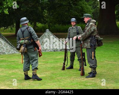 Tre fante del gruppo di reenactment in uniformi tedesche della seconda Guerra Mondiale con pistole. Foto Stock