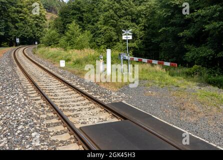 Sentiero forestale chiuso da una barriera prima di entrare nei binari. Foto Stock